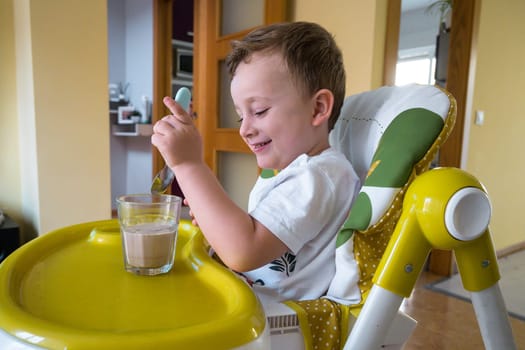 Beautiful child having breakfast with cereal and milk.