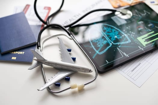 Modern social health insurance program. Tablet computer with healthcare application interface on screen. Stethoscope, x-ray image and cardiogram on wooden desk. Digital healthcare technologies