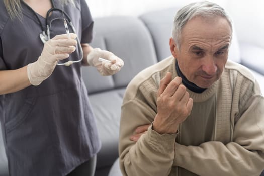 Doctor giving vaccination shot to elderly patient by syringe or injunction at home. concept of home health check to seniors during coronavirus covid-19 pandemic.