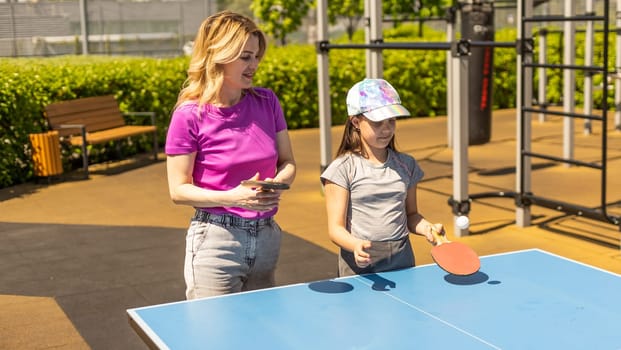 Young woman with her daughter playing ping pong in park.