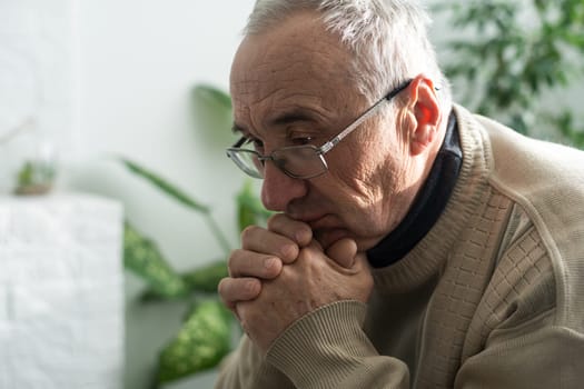Elderly caucasian man with interlocked fingers.