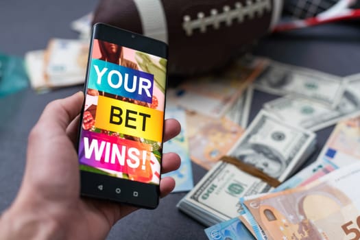 Sports betting website in a mobile phone screen, ball, money.
