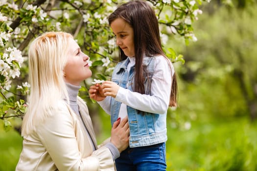 Happy woman and child in the blooming spring garden. Mothers day holiday concept