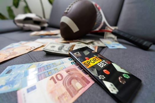 Online sports betting. Dollars are falling on the background of a hand with a smartphone and a soccer ball. Creative background, gambling