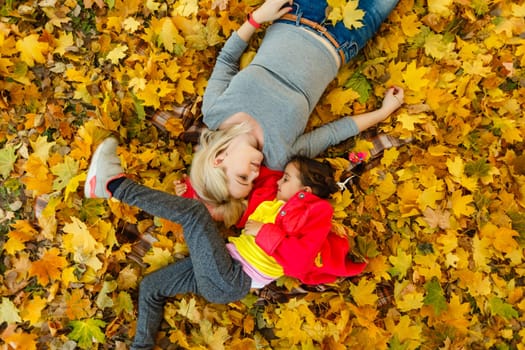 woman with daughter Outdoor having fun in autumn park.