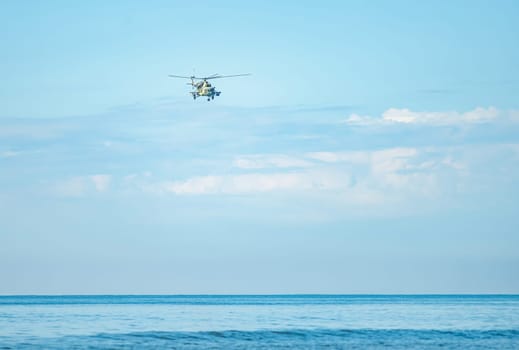 Military helicopter flying overhead on a clear day above the sea. attack helicopter flying the sky, with missiles, rockets and machine gun