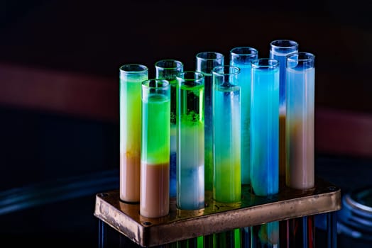 Colorful shot drinks in glass tubes. Dark background, atmospheric bar image. Laboratory glassware with alcohol cocktails on chemical party