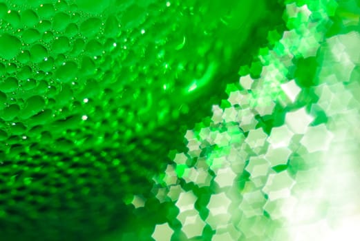 Green glass bottle, selective focus, beautiful blurred bokeh. Close-up. Drops of water on the glass passing in the bokeh in the form of a hexagonal star