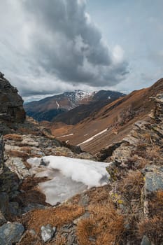 Vertical shot of a breathtaking view of a snow-covered valley among the slopes on a cloudy autumn day in the Pyrenees mountains. The concept of beautiful Spanish mountain nature.