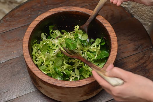 Wood bowl of fresh salad on a wooden table