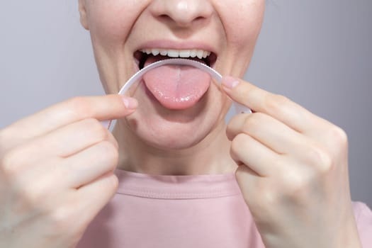 Closeup Of Woman Cleaning Her Tongue With Plastic Flexible Tongue Scraper, Cleaner. Dentistry, dental care concept Horizontal Plane. Selective Focus. High quality photo