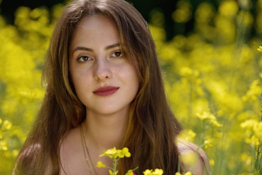 Portrait of a beautiful young woman surrounded by canola flowers.  Close-up.
