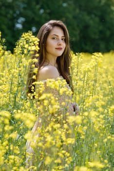 Portrait of a beautiful young woman surrounded by canola flowers.