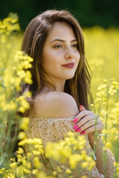 Portrait of a beautiful young woman surrounded by canola flowers.