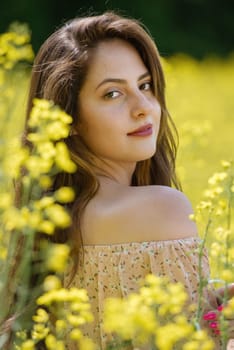 Portrait of a beautiful young woman surrounded by canola flowers.