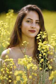 Portrait of a beautiful young woman surrounded by canola flowers.