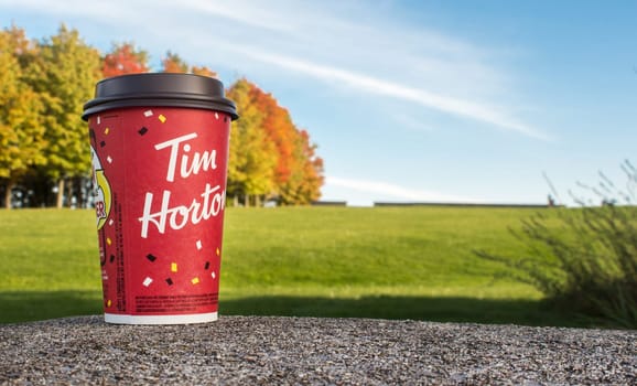 Red Paper Tim Hortons cup of coffee Winning game cup autumn trees on background. Fresh morning coffee. Ottawa, ON, Canada - 20.10.2022.