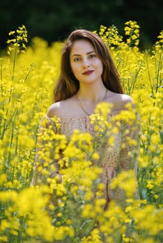 Portrait of a beautiful young woman surrounded by canola flowers.