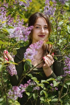 Portrait of a beautiful young woman surrounded by lilac flowers.