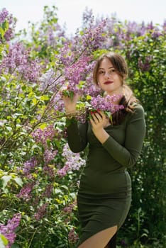 Beautiful young woman surrounded by lilac flowers.
