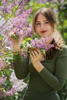 Portrait of a beautiful young woman surrounded by lilac flowers.