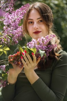 Portrait of a beautiful young woman surrounded by lilac flowers.