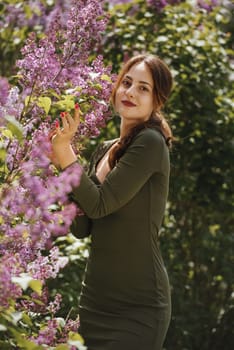 Beautiful young woman surrounded by lilac flowers.