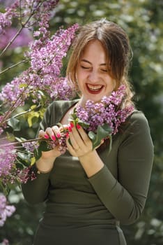 Portrait of a beautiful young woman surrounded by lilac flowers.