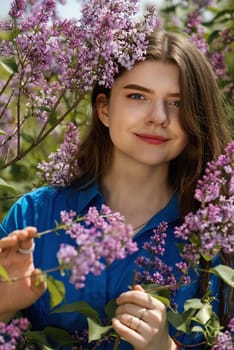 Portrait of a beautiful young woman surrounded by lilac flowers.