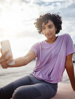 Fitness, exercise and woman taking a selfie on a phone while doing outdoor workout in the city. Healthy, young and girl athlete from puerto rico taking picture on smartphone while doing yoga on a mat.