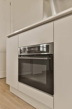 a kitchen with white cupboards and an oven in the corner, taken from the side to the other space