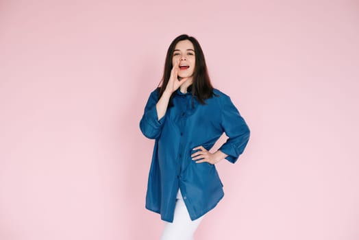 Excited Girl Sharing Breaking News: Hand Near Open Mouth Conveying Surprise and Delivering Important Information in an Empty Space, Isolated on a Pink Background.