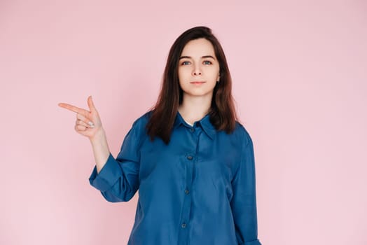 Positive Woman Pointing with Finger, Sharing Useful Tips in Empty Space: Conceptual Photo on Pink Background.