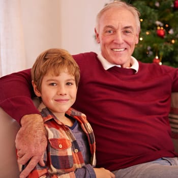 Elderly man, grandson and christmas portrait on sofa with love, bonding or happiness in family home. Boy, grandfather and smile together for celebration, holiday or happy on couch in house by tree.