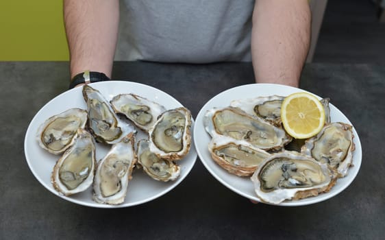 Man hands with lemon and oyster on a black background