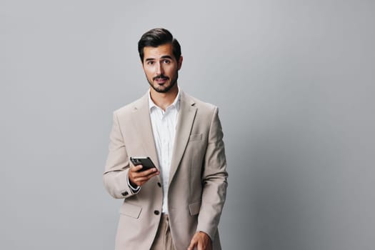 man suit young online smile happy message phone portrait handsome smartphone entrepreneur application male hold app businessman background call gray business