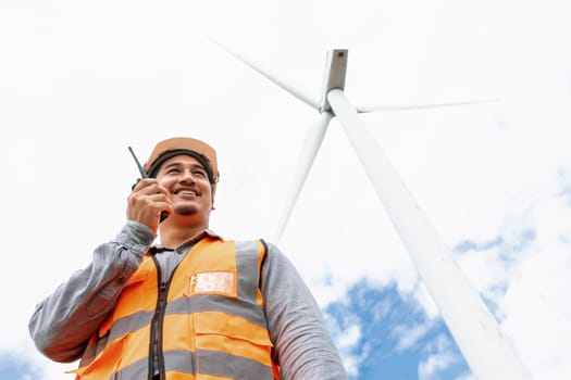 Engineer working on a wind farm atop a hill or mountain in the rural. Progressive ideal for the future production of renewable, sustainable energy. Energy generation from wind turbine.