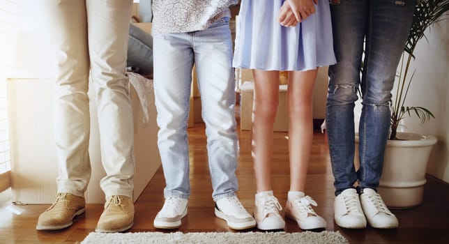 Love, family and closeup of people with shoes standing in a line in the living room of their home. Bonding, together and zoom of couple and children legs in a row in the lounge of their modern house