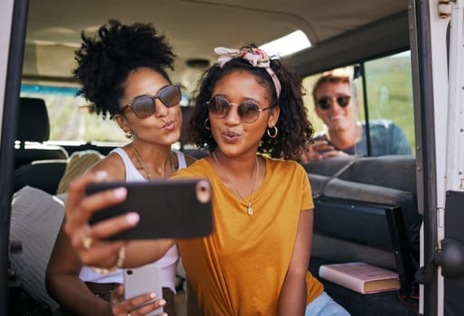 Selfie, phone and road trip with girl friends taking a photograph while sitting in a car or van on vacation. Mobile, social media and transportation with a female and friend posing for a picture.