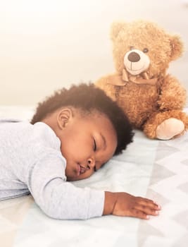 Sleeping, teddy bear and relax with baby in bedroom for carefree, development and innocence. Dreaming, cute and comfortable with african infant and toy at home for morning, resting and bedtime.