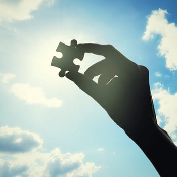 Hand, puzzle and solution with clouds in sky with problem solving, lens flare or bright ideas in sunshine. Silhouette, jigsaw and light for strategy, innovation or synergy for connection with person.