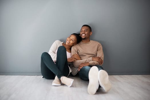 Apartment, love and couple on floor with wall background relax, rest and bond after moving in new home together. Real estate, dating and young black couple in living room thinking of house design.