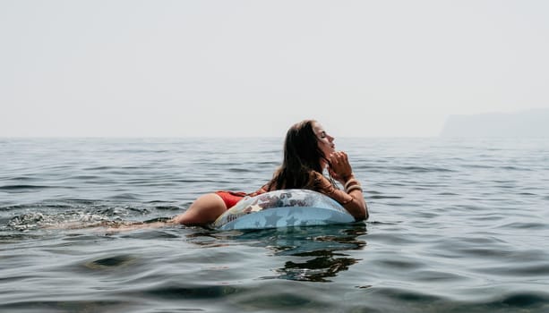 Woman summer sea. Happy woman swimming with inflatable donut on the beach in summer sunny day, surrounded by volcanic mountains. Summer vacation concept