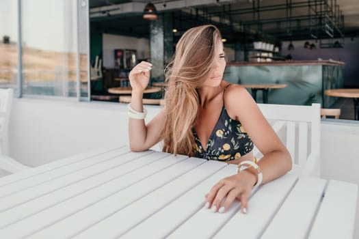 Happy woman portrait in cafe. Boho chic fashion style. Outdoor photo of young happy woman with long hair, sunny weather outdoors sitting in modern cafe