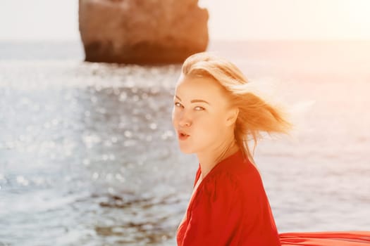 Woman travel sea. Young Happy woman in a long red dress posing on a beach near the sea on background of volcanic rocks, like in Iceland, sharing travel adventure journey