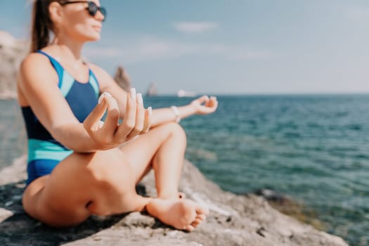 Woman sea yoga. Back view of free calm happy satisfied woman with long hair standing on top rock with yoga position against of sky by the sea. Healthy lifestyle outdoors in nature, fitness concept.