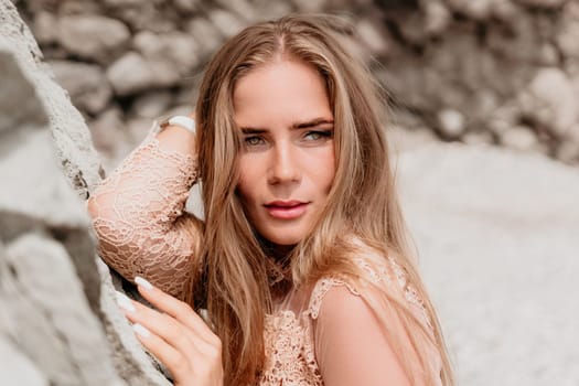 Woman travel sea. Young Happy woman in a long red dress posing on a beach near the sea on background of volcanic rocks, like in Iceland, sharing travel adventure journey