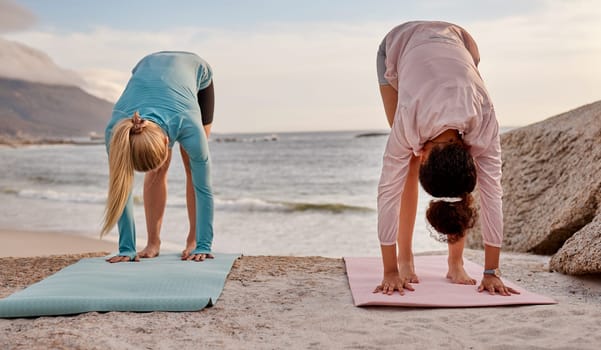 Pilates, fitness and woman friends on the beach together for mental health, wellness or balance in summer. Exercise, diversity or nature with a female yogi and friend practicing yoga outside.