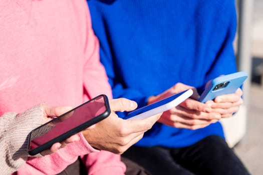 close up of the hands of three young adults using mobile phones, concept of modern urban lifestyle and technology of communication, copy space for text