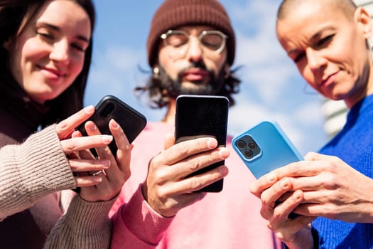 three young friends using mobile phones, focus on the hands, concept of modern lifestyle and technology of communication